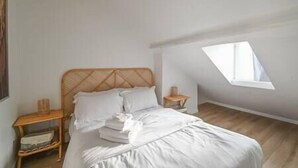 A bedroom with a bed, a nightstand, and a window. - Romantic apartment in central Paris (Paris)