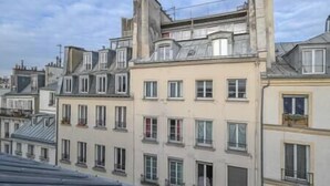 A row of multi-story buildings with uniform window patterns and balconies. - Romantic apartment in central Paris (Paris)