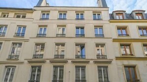 A multi-story building with a symmetrical facade, featuring evenly spaced windows and balconies. - So cute typical french apartment (Paris)