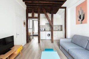 Uma sala de estar moderna com um sofá cinzento, uma mesa de centro de madeira e uma TV sobre um suporte de madeira.