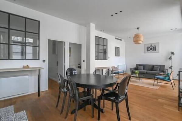 A modern living space with a dining area, a sofa, and a lamp.