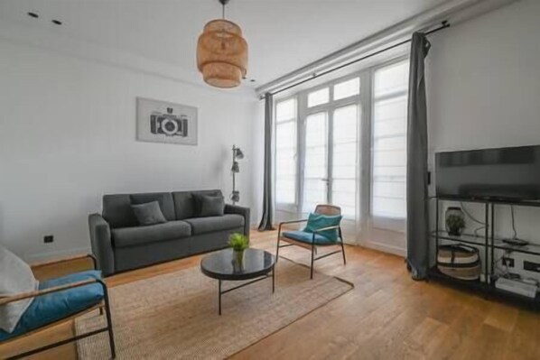 A modern living room with a sofa, two armchairs, a coffee table, and a television. - To complete (Paris)