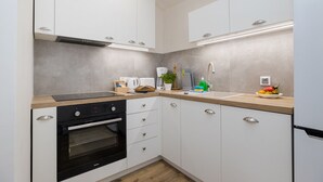 A modern kitchen with white cabinets, a built-in oven, a coffee machine, and a sink with a faucet. - ShortStayPoland Zelazna B146 (Warsaw)