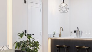 Una cocina moderna con una isla central, taburetes de bar y una lámpara colgante.