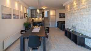 Una cocina moderna con comedor, que incluye una mesa larga, sillas y una escalera que conduce a un nivel superior.