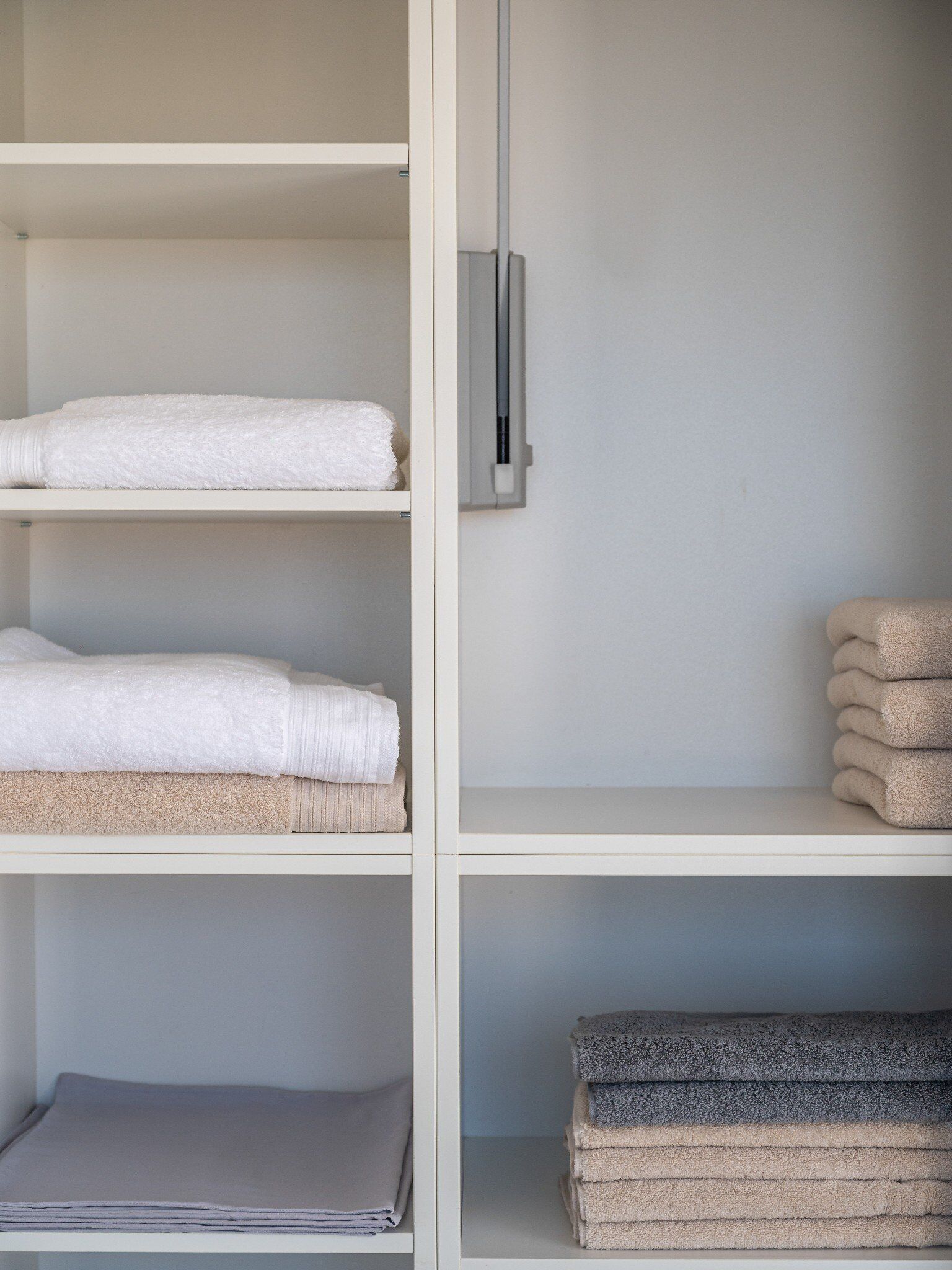 A neatly organized storage unit with shelves holding folded towels in various colors.