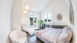 Un dormitorio con cama, una silla, un escritorio y un ventanal grande.