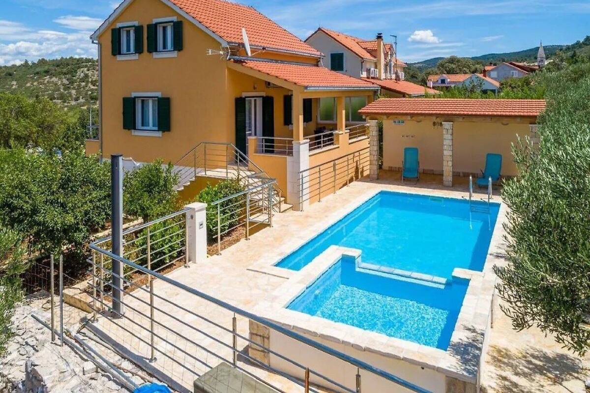 A two-story house with a swimming pool, a balcony, and a view of the surrounding landscape.