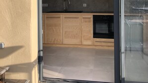 A modern kitchen with wooden cabinets, a black sink, and a glass door leading to a patio area. - A Mas in the Parc des Cévennes with breathtaking views over the Hérault valley (Saint Julien de la nef)