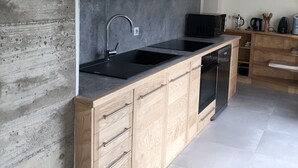 A modern kitchen with wooden cabinets, a black sink, and a built-in oven. - A Mas in the Parc des Cévennes with breathtaking views over the Hérault valley (Saint Julien de la nef)