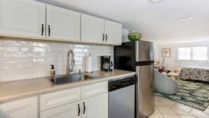 Una cocina moderna con armarios blancos, un refrigerador de acero inoxidable, una cafetera y un lavavajillas.