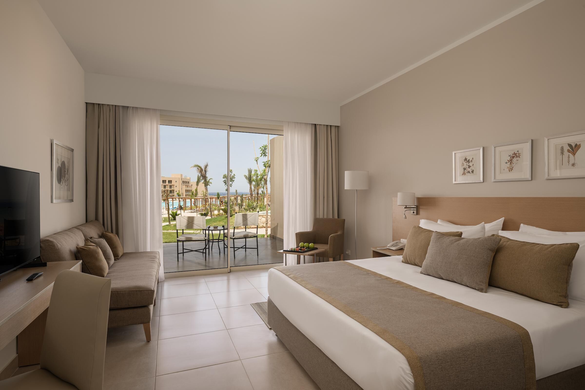 Une chambre d’hôtel avec un grand lit, une télévision, un bureau et un balcon donnant sur la piscine.
