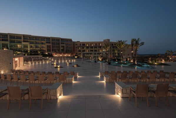 A hotel courtyard with outdoor seating, a pool, and a building with multiple floors and balconies.