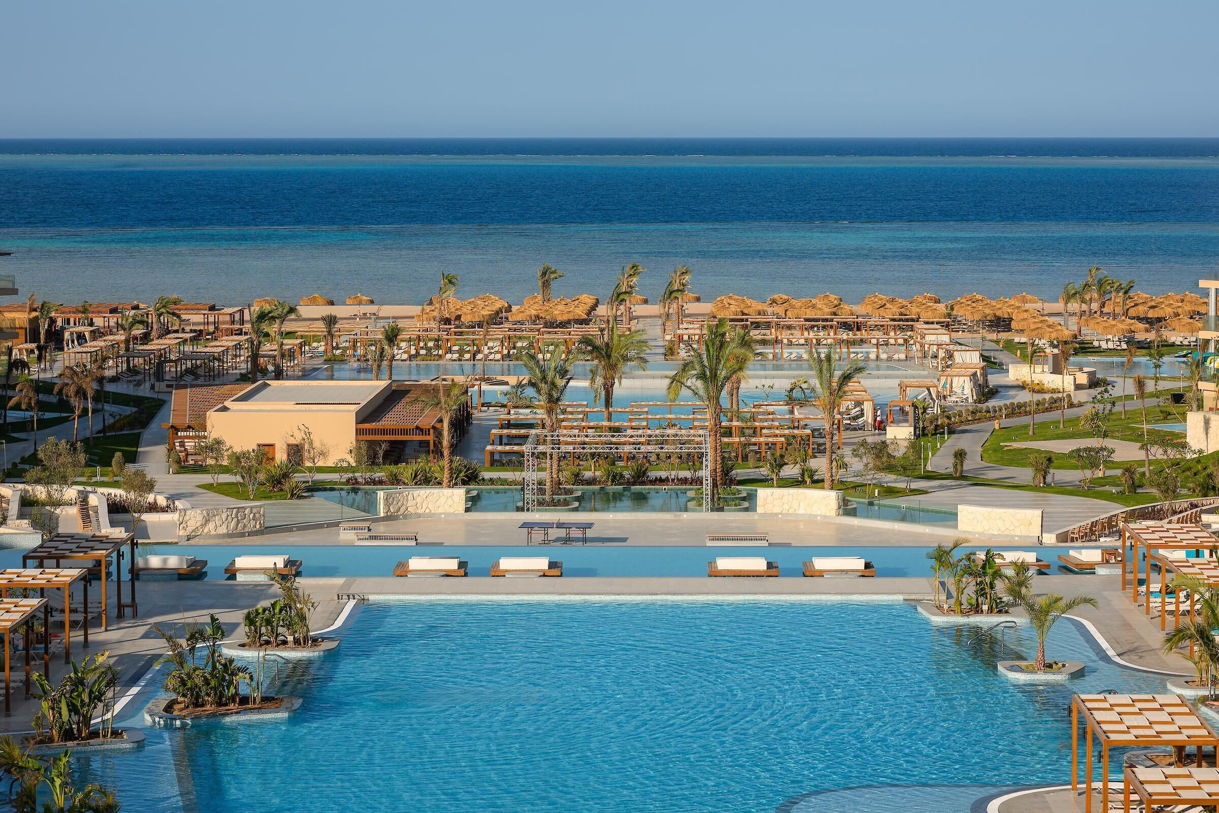 Un resort con una piscina grande, palmeras y vistas al océano.