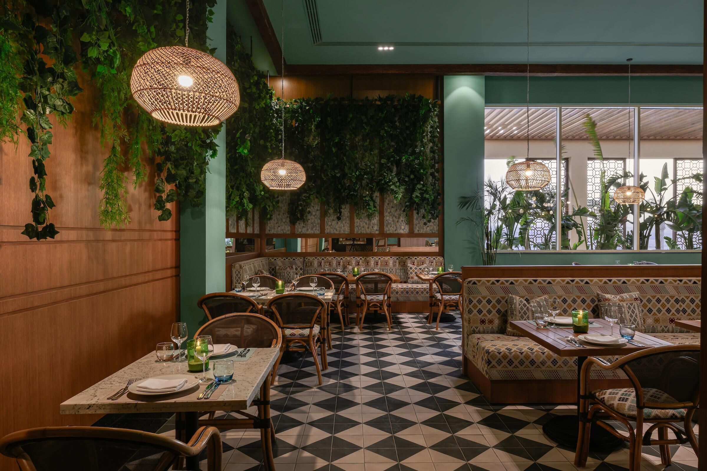 Un restaurant au sol à carreaux, avec des meubles en bois et des lampes en osier suspendues au plafond.