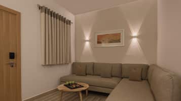 Una sala de estar moderna con un sofá color beige, una pequeña mesa redonda y una puerta con picaporte.