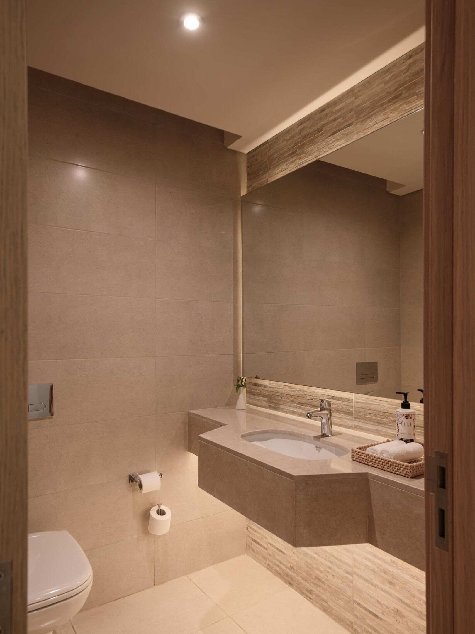 A modern bathroom with a large mirror, a sink, and a toilet.