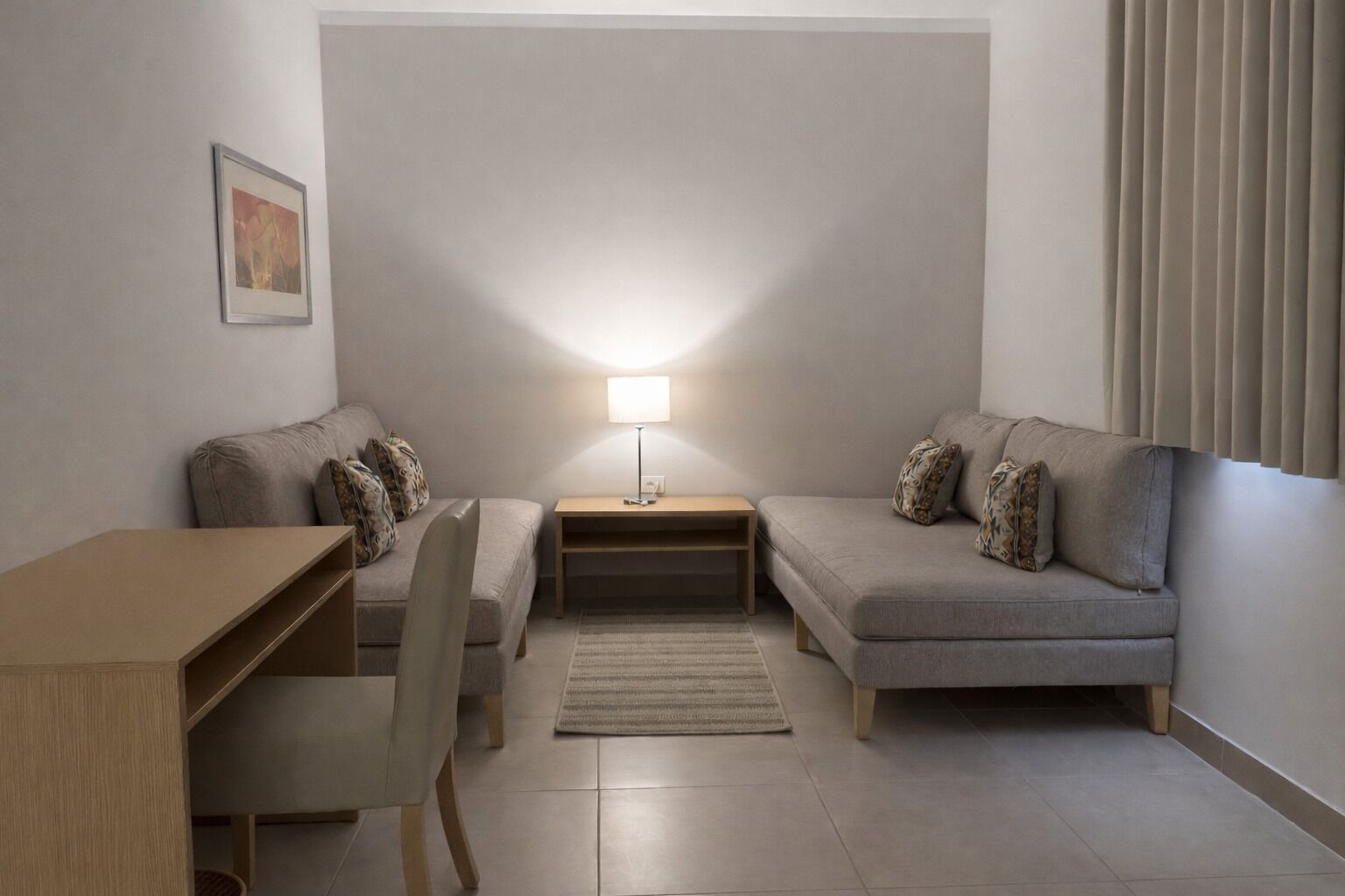 Un espacio habitable compacto con un sofá, una mesita, una silla y una lámpara.