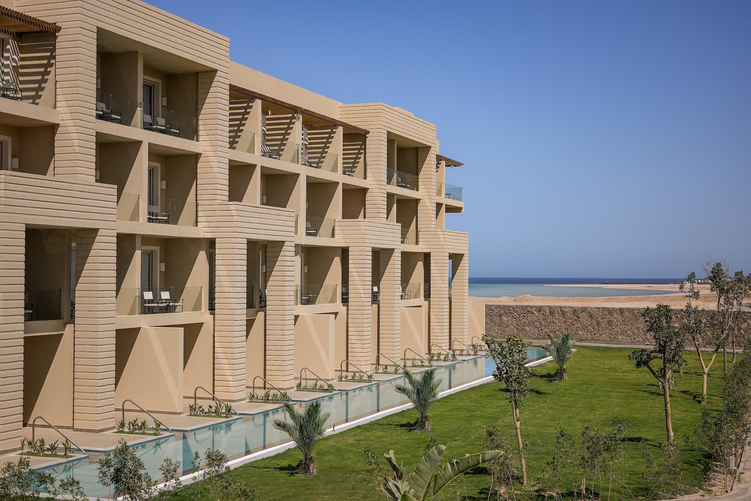 Un hotel de varios pisos con balcones, una piscina y vistas a la playa.