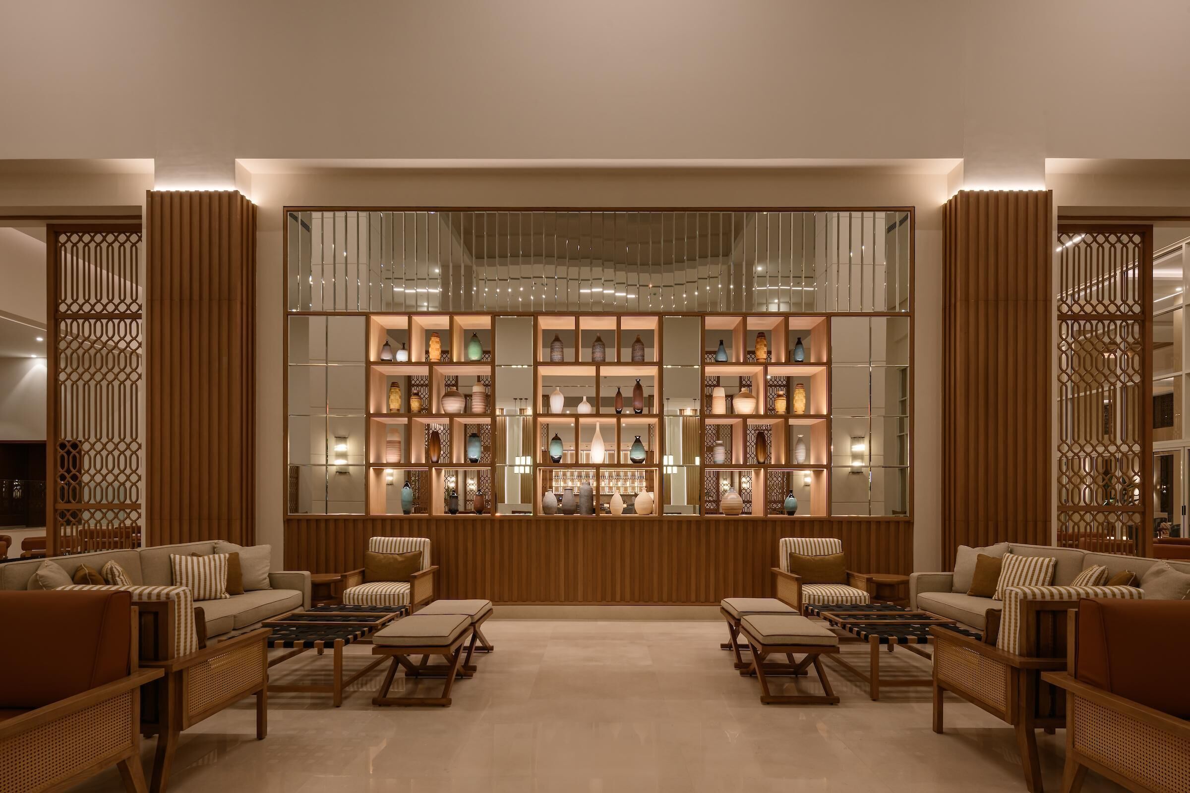Un interior moderno con una exhibición central de objetos decorativos, asientos acolchados y paneles de madera.