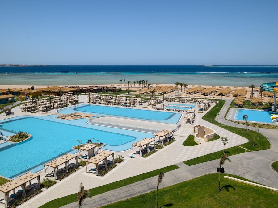 Un resort con varias piscinas, un tobogán de agua y una zona de playa.