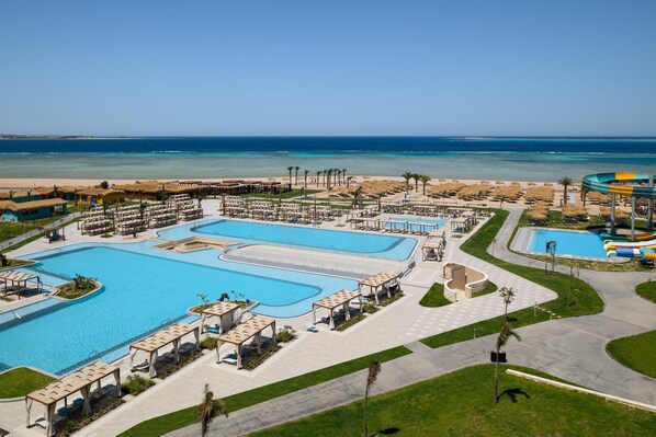 Un resort con varias piscinas, un tobogán de agua y una zona de playa.