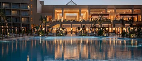 Un hotel con una piscina amplia, varios pisos y una entrada destacada.