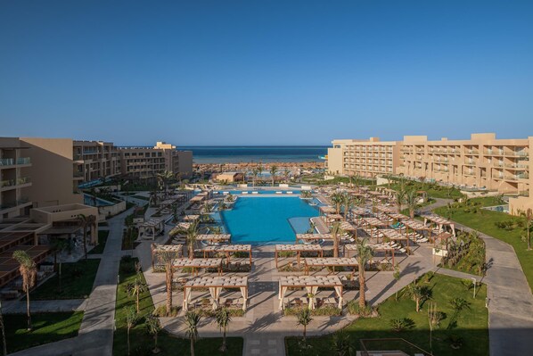 Un resort con piscina central, varias habitaciones de huéspedes y vista a la playa.