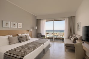 A hotel room with a large bed, a desk with a TV, a balcony with a pool view, and framed artwork on the wall.