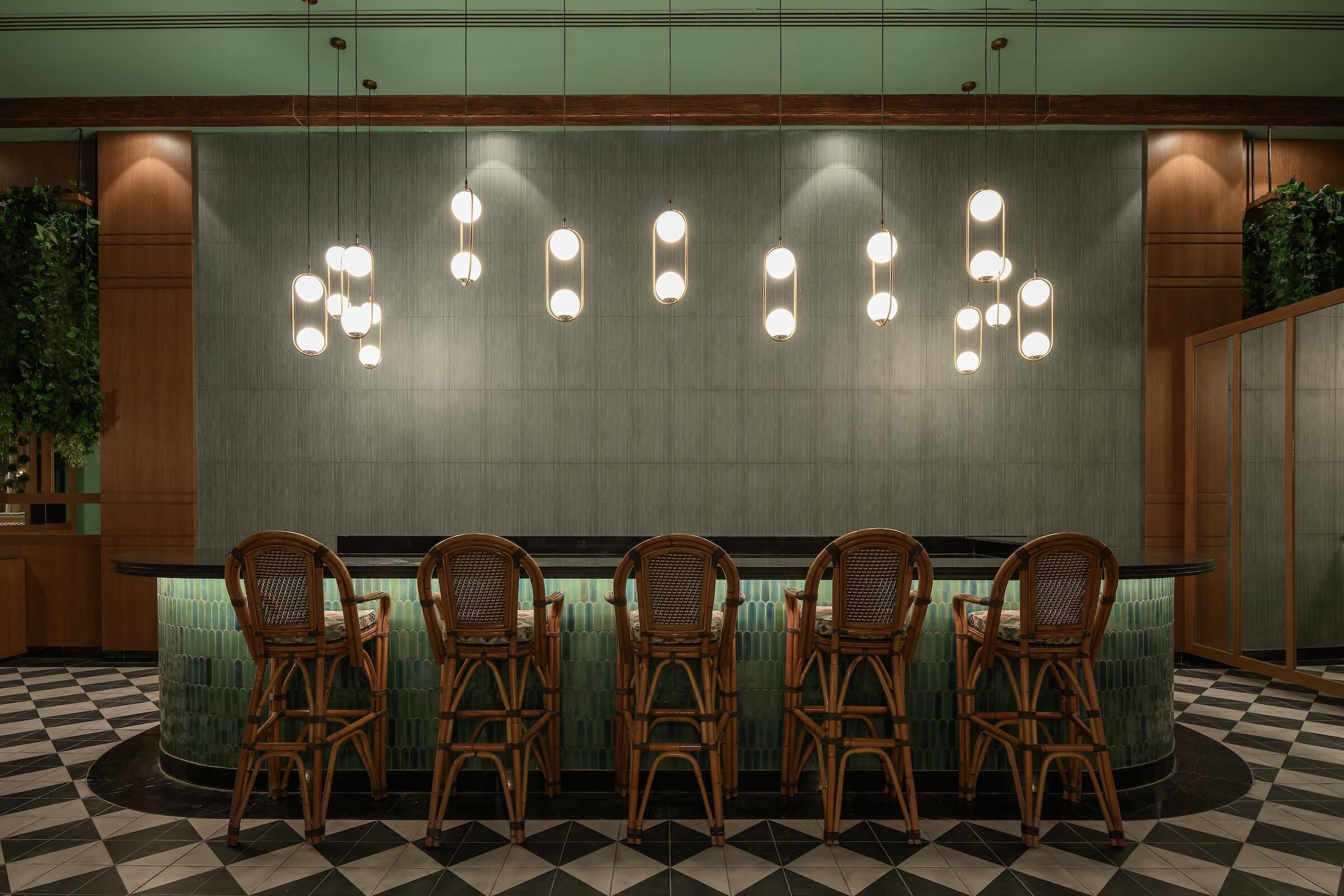 A reception area with a checkered floor, a green wall, and a row of wicker chairs.