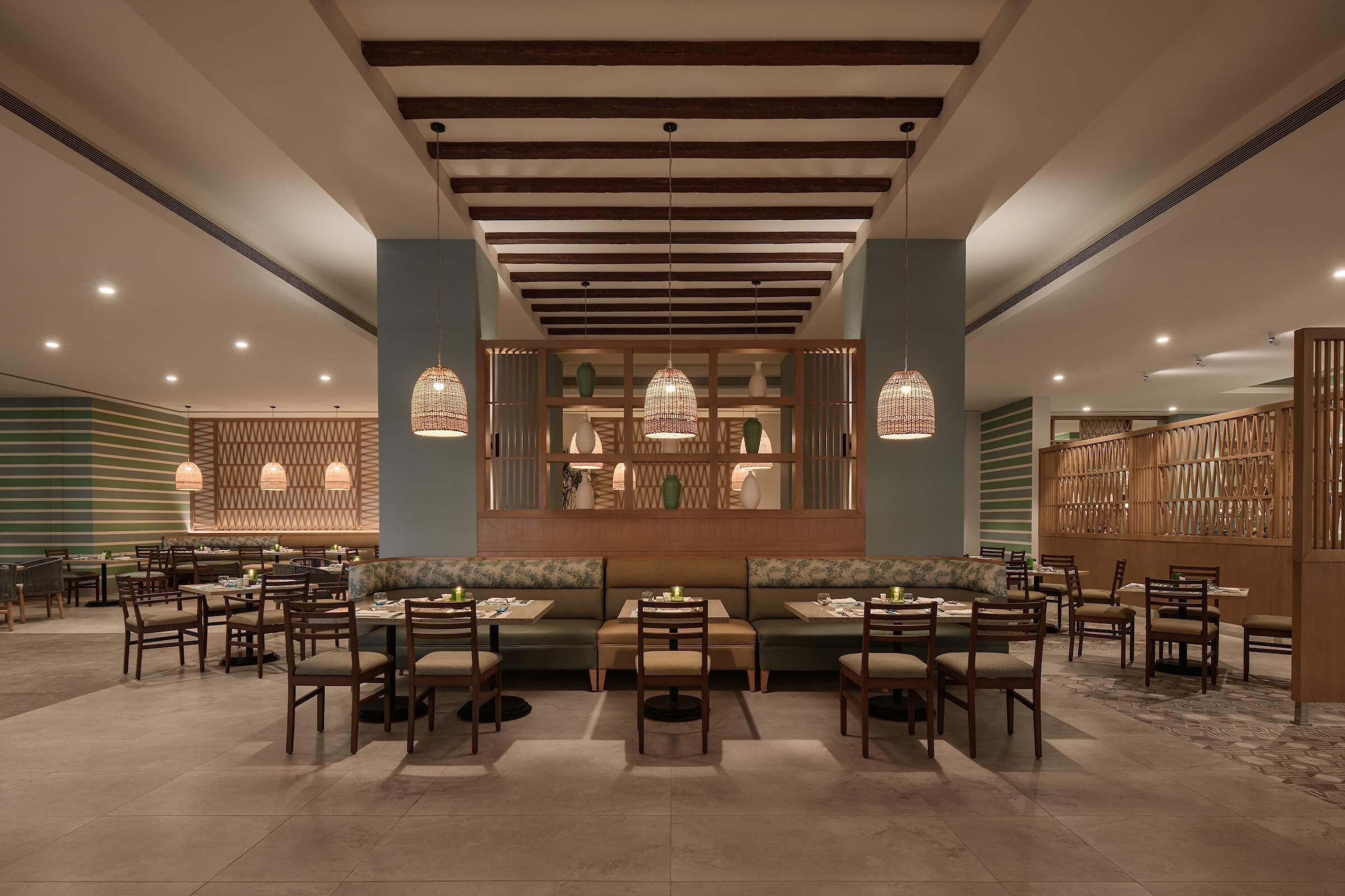 A restaurant with a central seating area, multiple tables, and hanging pendant lights.