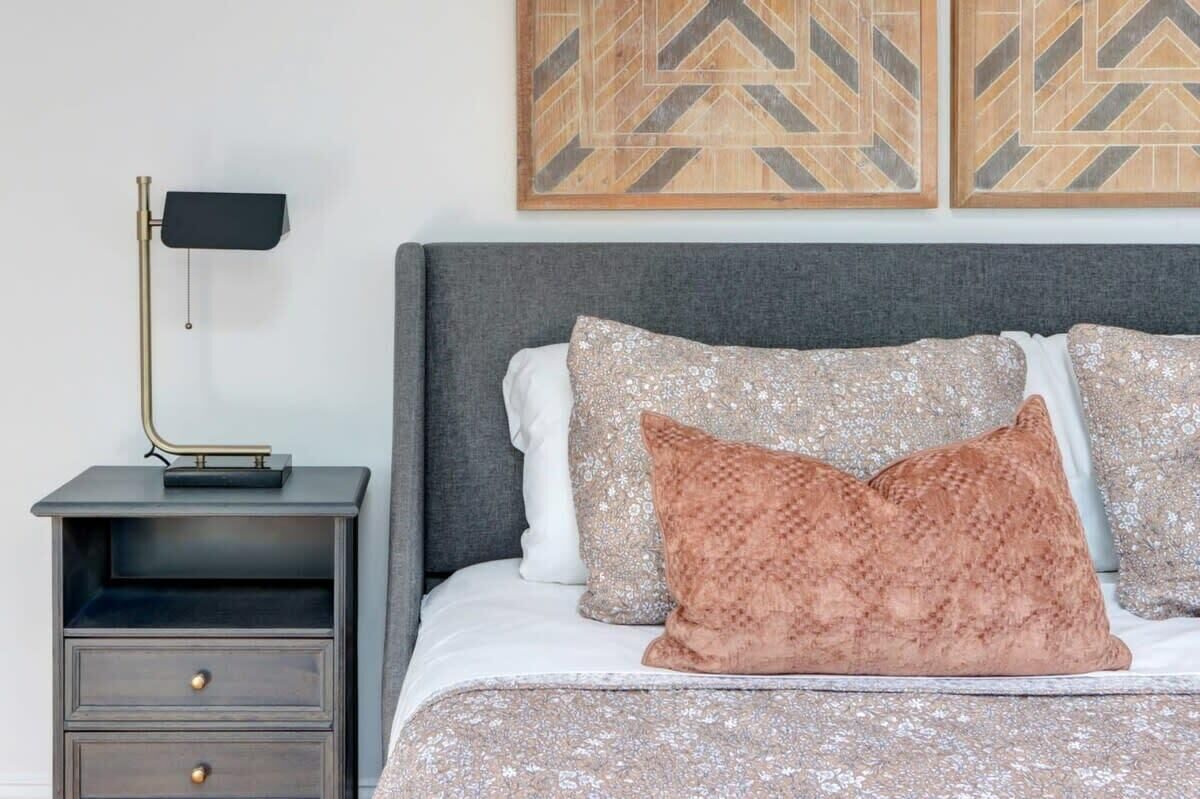 A bedroom with a bed, a nightstand, a lamp, and two wall art pieces.
