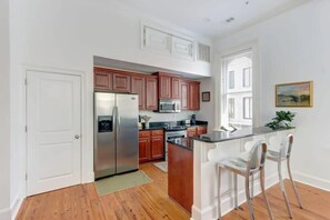 A kitchen with wooden cabinets, stainless steel appliances, and a bar area with two bar stools.