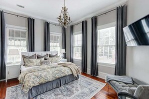 Ein Schlafzimmer mit einem großen Bett, einem an der Wand befestigten Fernseher und einem Sofa.