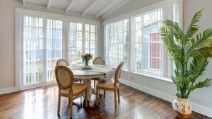A dining area with a round table, four chairs, and a potted plant. - Avery's Cottage @ Trustees' Garden | Walk 2 River! (Savannah)