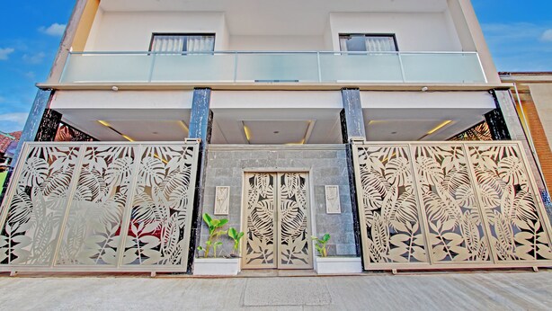 Ein modernes, zweistöckiges Gebäude mit Balkon, schmiedeeisernen Zäunen und Pflanzkübeln.