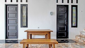 Ein Zimmer mit zwei schwarzen Türen, einem Holztisch und einem Marmorboden.