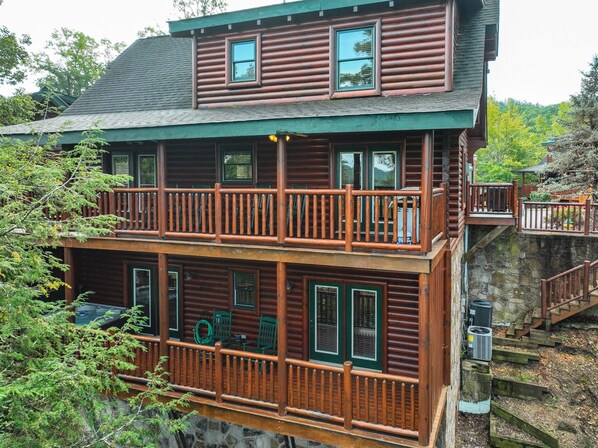 A two-story log cabin with a balcony and outdoor seating area. - Log cabin convenient to Dollywood, Townsend, & National Park (Sevierville)