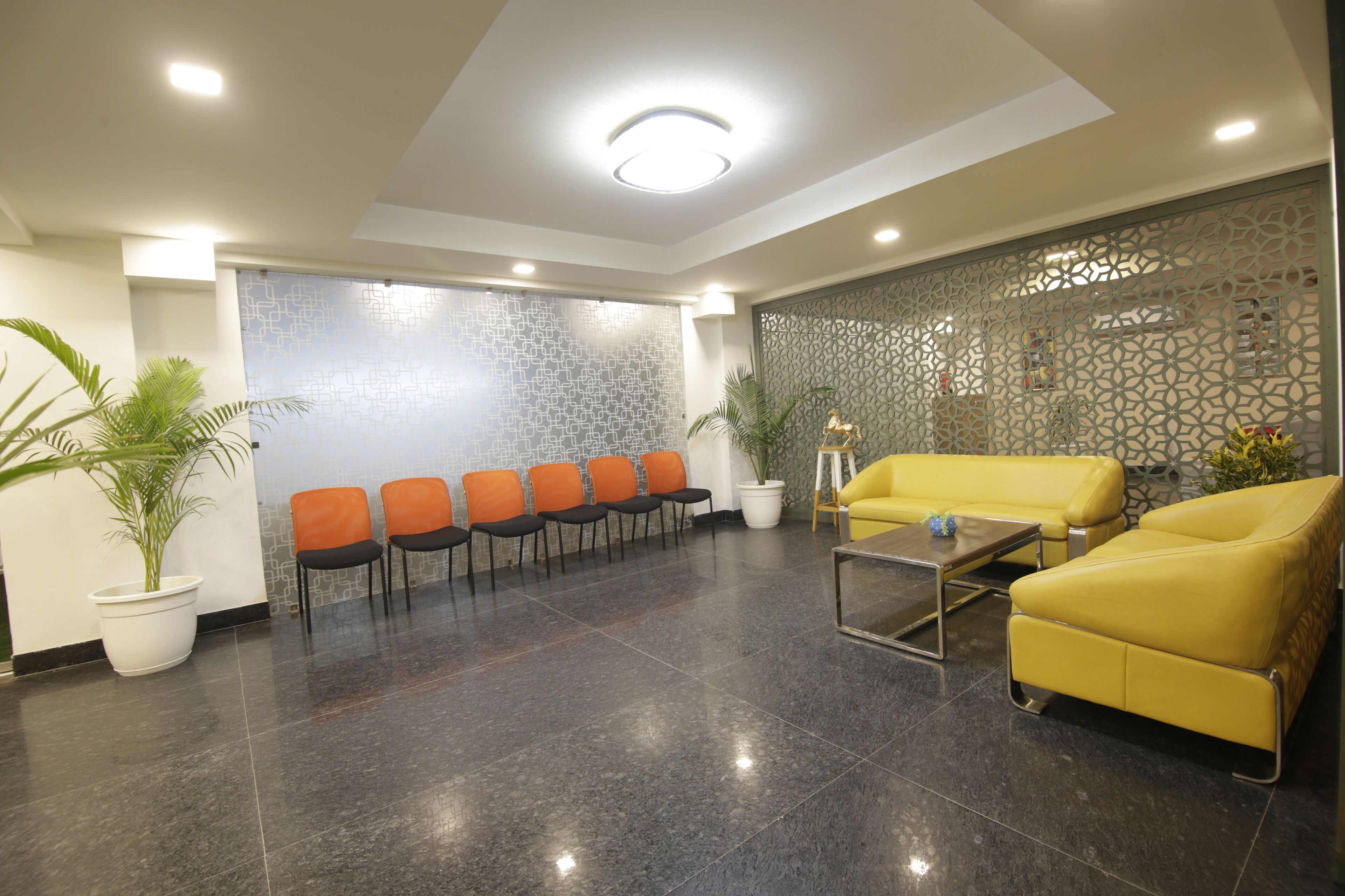 Un espace d’accueil comprenant un coin salon, un mur décoratif et une plante en pot.