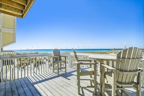 Eine Holzterrasse mit zwei Adirondack-Stühlen mit Blick auf den Strand.