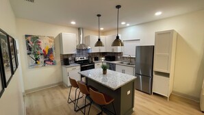 Una cocina moderna con armarios blancos, electrodomésticos de acero inoxidable y encimera de granito.