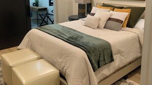 Un dormitorio con cama, mesita de noche, espejo, ventilador de techo y alfombra estampada.