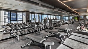 Ein modernes Fitnessstudio mit diversen Trainingsgeräten, großen Fenstern und hoher Decke.