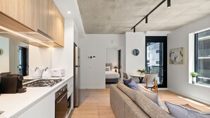 Eine moderne Küche mit Einbauherd, weißen Schränken und einem Essbereich mit Sofa und Stühlen.