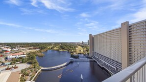 A high-rise hotel with a view of a lake and surrounding greenery. - Waterfront 1BR condo w/ balcony & resort pools (Panama City Beach)