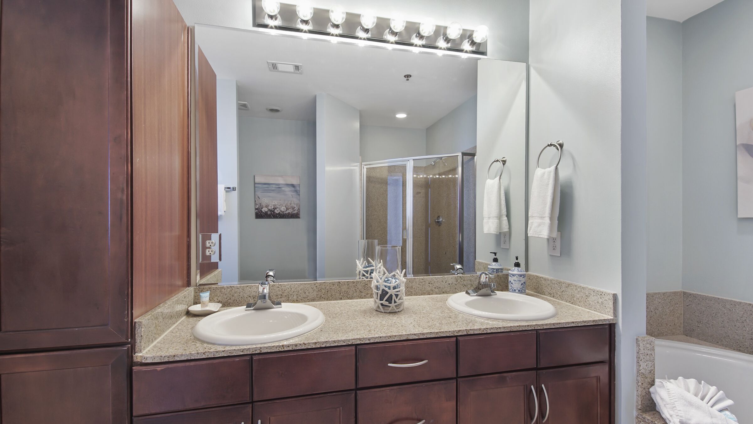 A bathroom with two sinks, a large mirror, and a vanity with drawers.