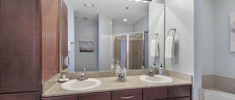 A bathroom with two sinks, a large mirror, and a vanity with drawers.