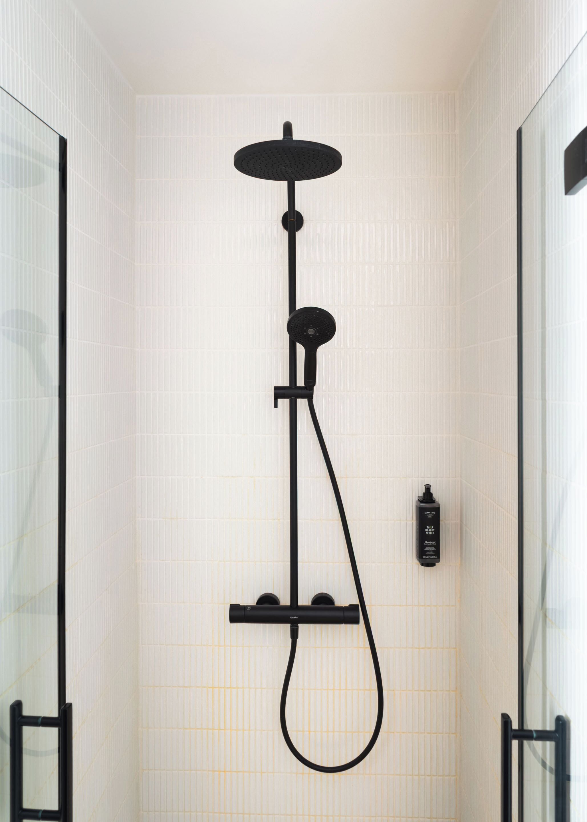 Une douche moderne équipée d’un pommeau de douche à main, d’un pommeau de douche à pluie et d’un appareil de massage portatif.