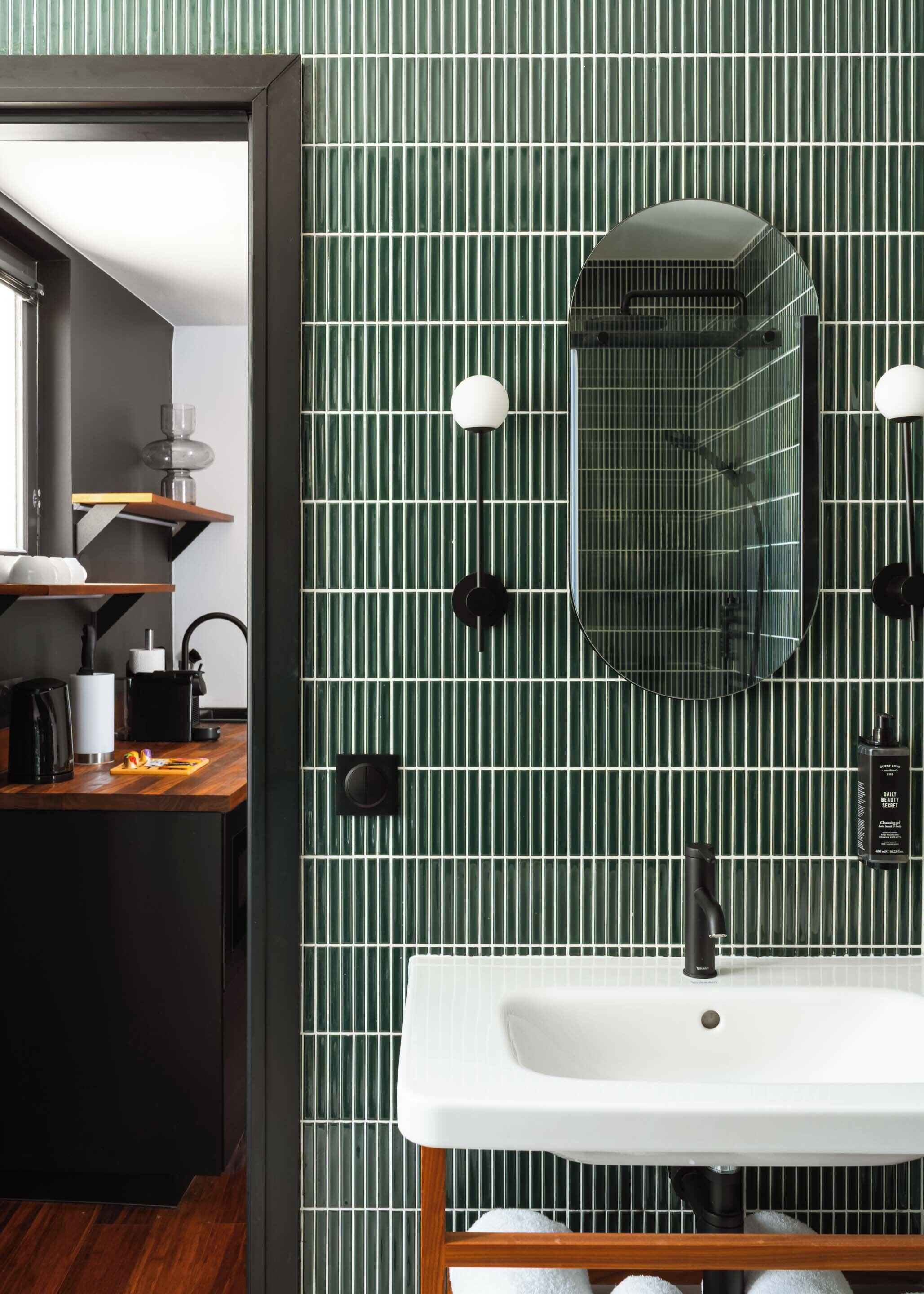 A modern bathroom with a green striped wall, a white sink, and a mirror above it.