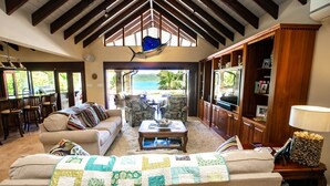 A spacious living room with a high ceiling, a large window overlooking a scenic view, a cozy sofa, a coffee table, and a television.